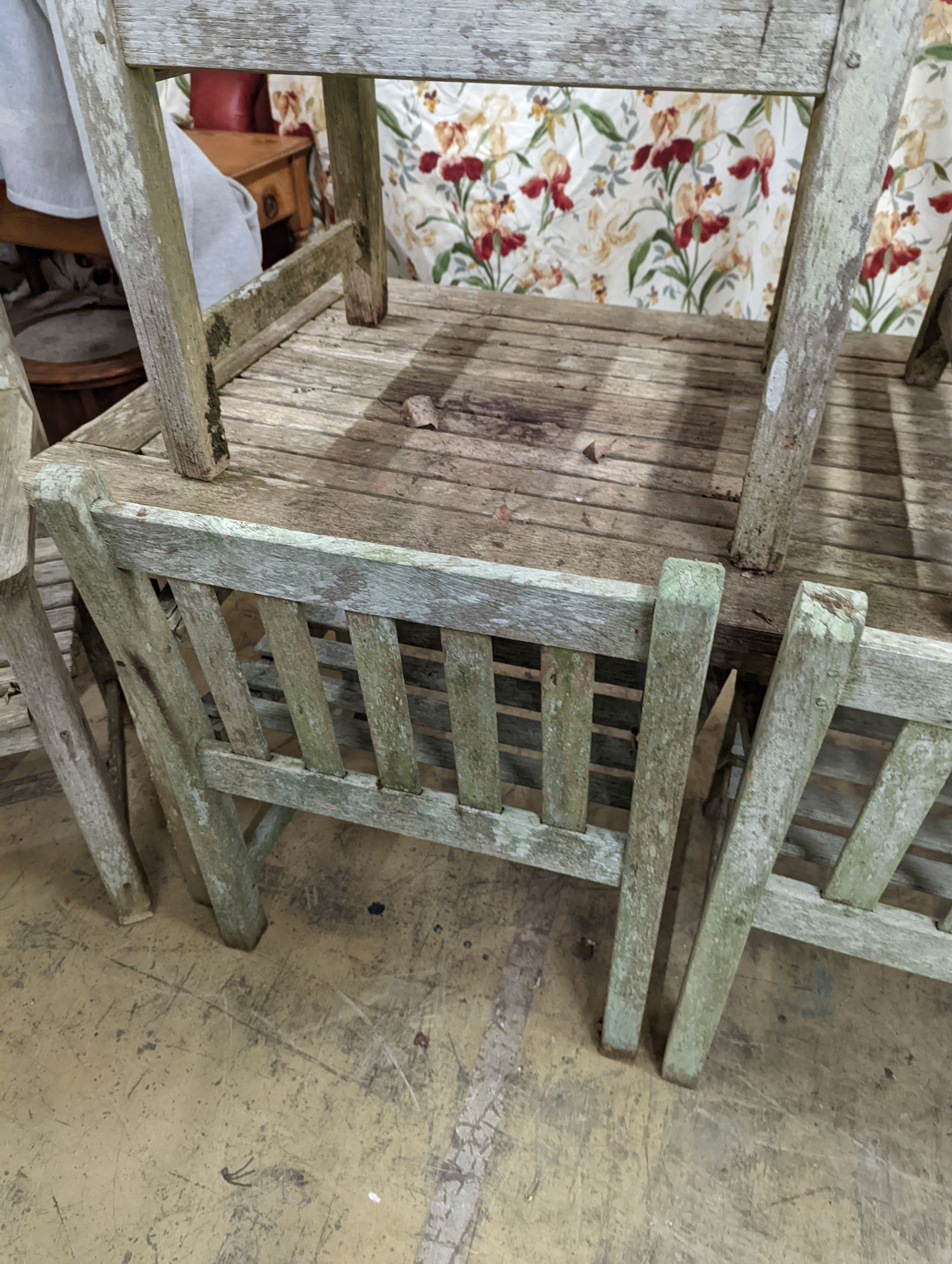 A weathered teak rectangular garden table and six elbow garden chairs, not matching. Table measures, W-149cm, D-70cm, H-75cm.